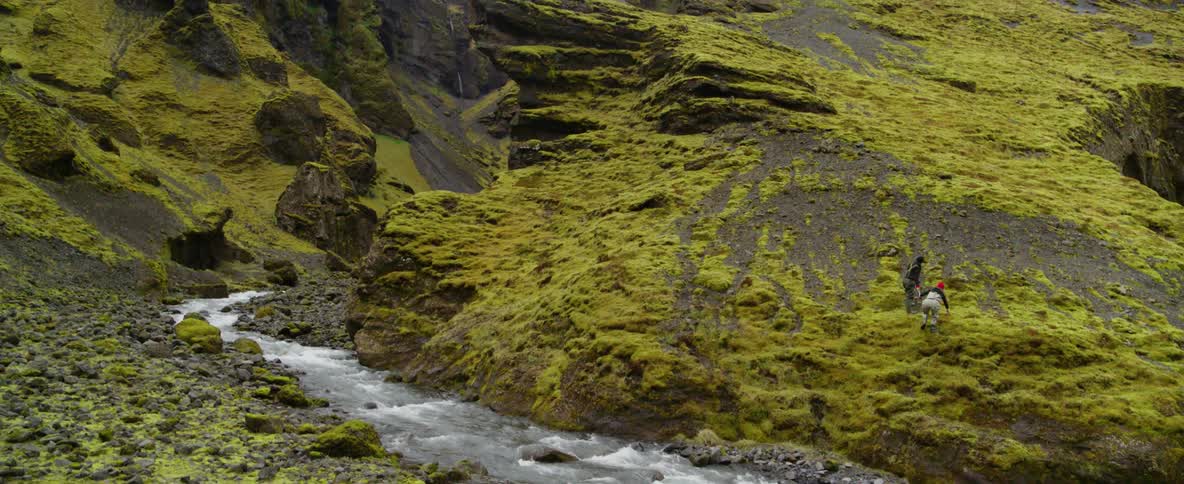 A stream of water splashes through rocky mossy mountains