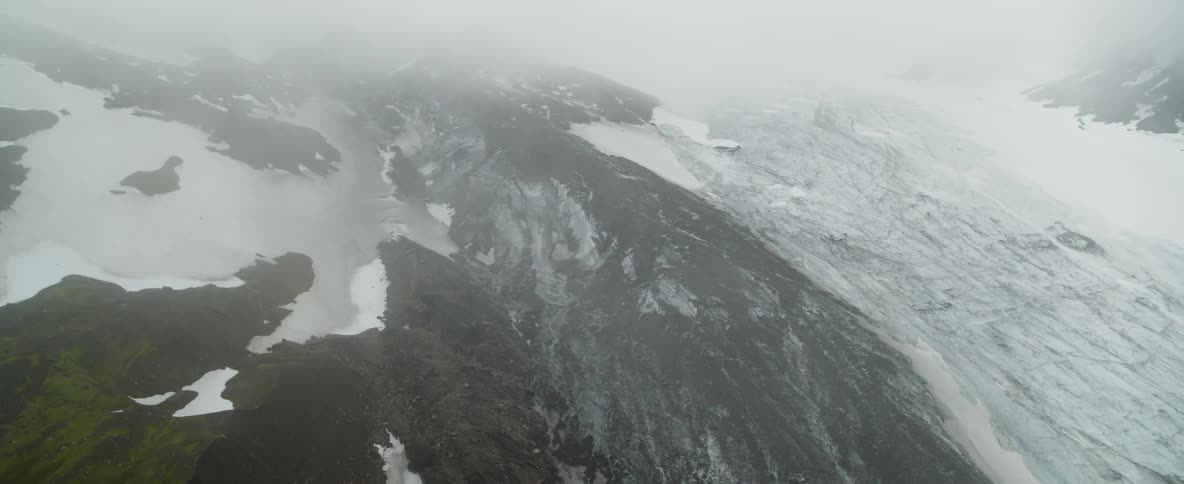 Clouds float over a snowy mountain landscape