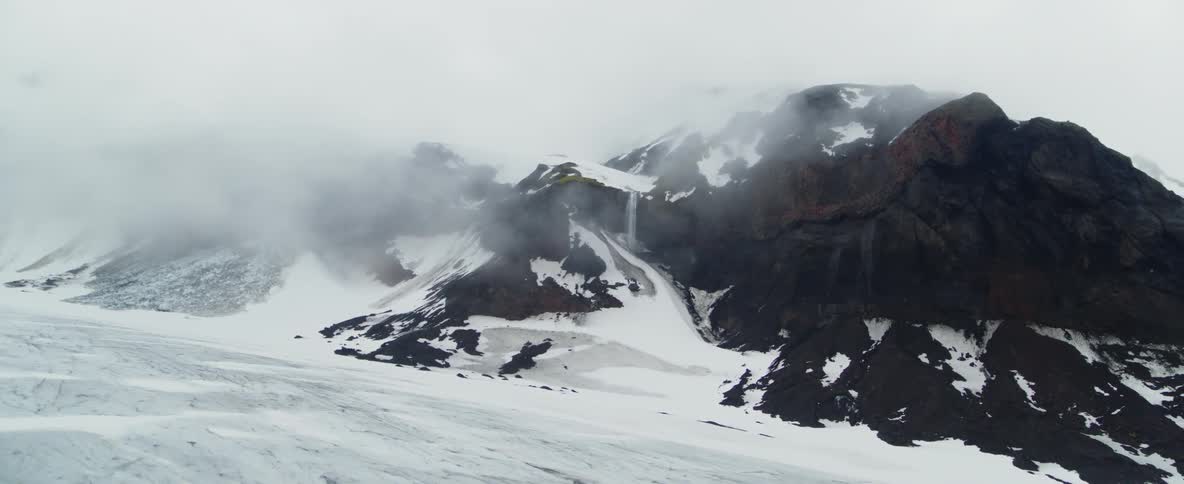 Clouds hang over snow and ice covered peaks
