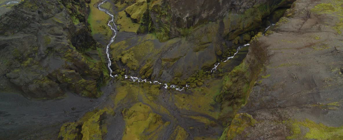 A river flows through mossy mountains