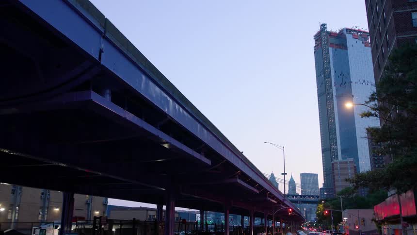 A skyscraper is under construction in a city at dusk