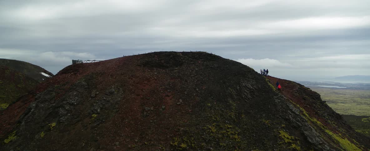 Hikers climb a mountainside on a cloudy day