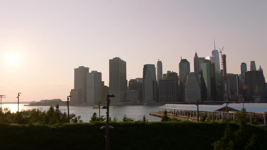 Skyscrapers stand next to a river at sunset