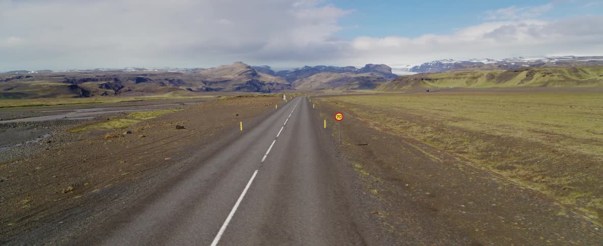 A rural mountain road is shown on a cloudy day