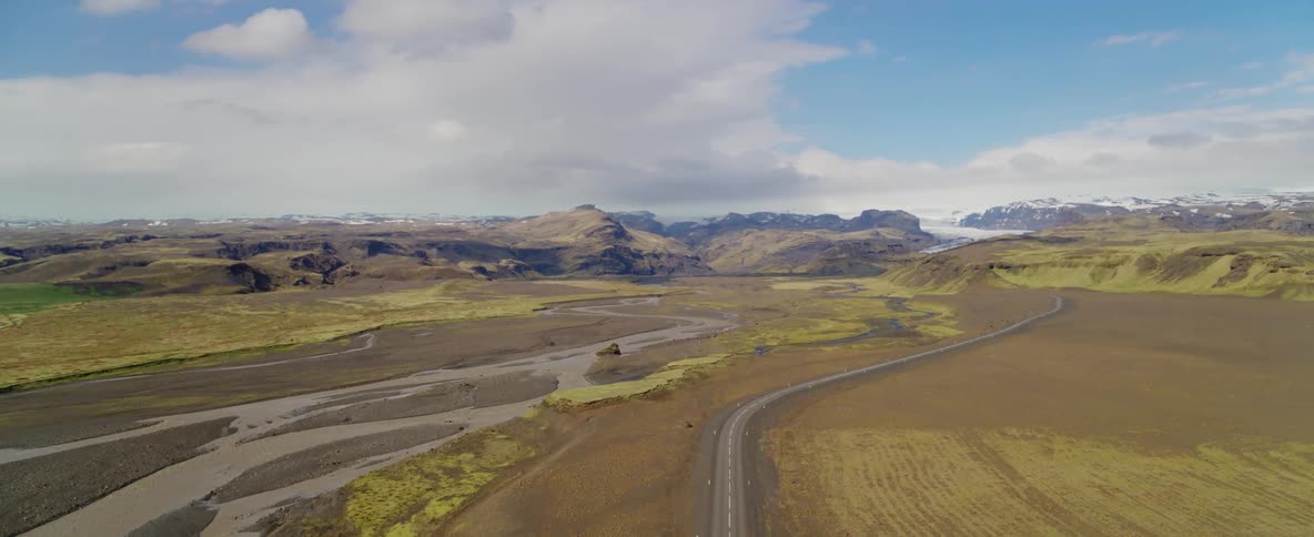Clouds hover over a mountain range and rural road