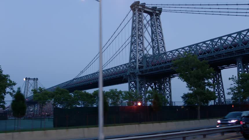 Vehicles drive under a bridge at dusk