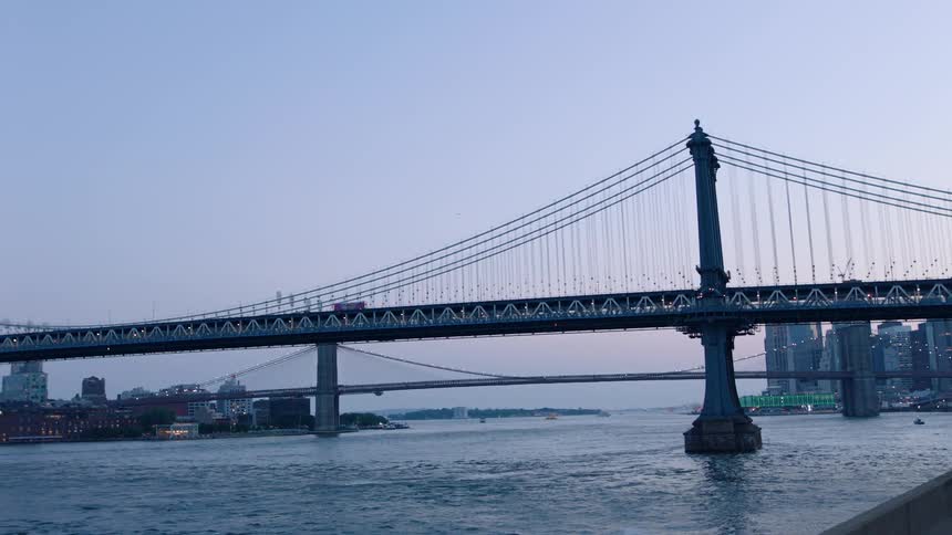 Water flows under two city bridges at sunset