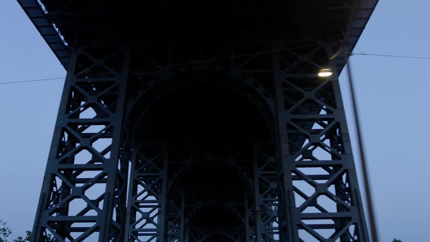 A cable bridge stands above a city street at dusk