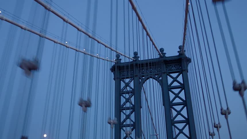 Cars are passing through the brooklyn bridge at sunset