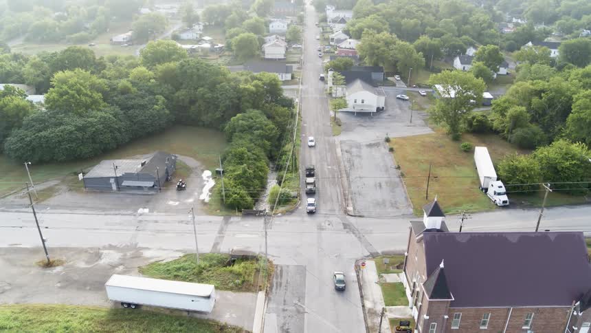 A police car leads two military vehicles down a neighborhood road