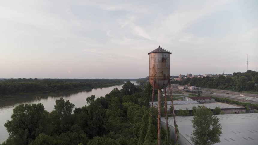 A rusty water tower near a river