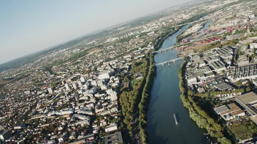 Barges float down a river in a city during the day