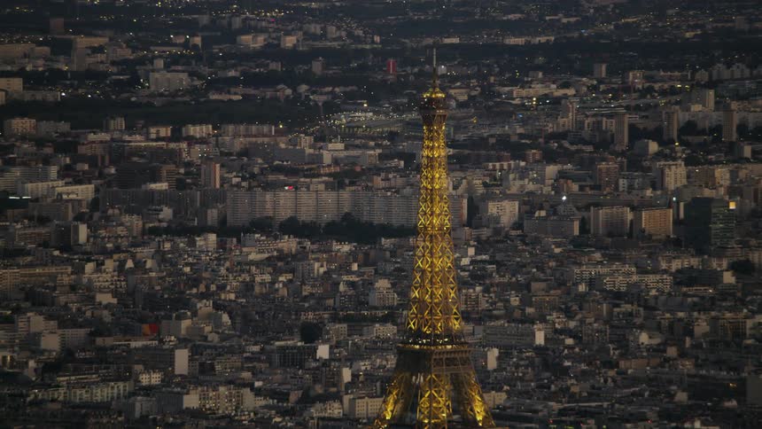 The eiffel tower is illuminated by lights at dusk