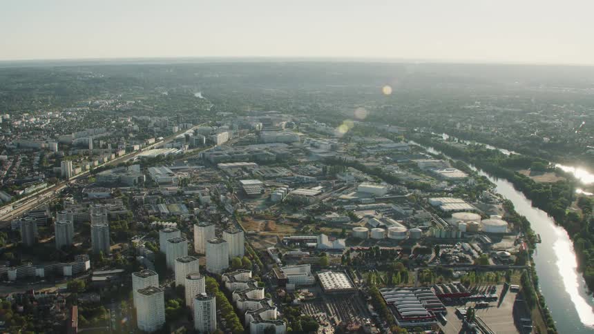 Sunlight is gleaming off a river flowing through an urban area during the day