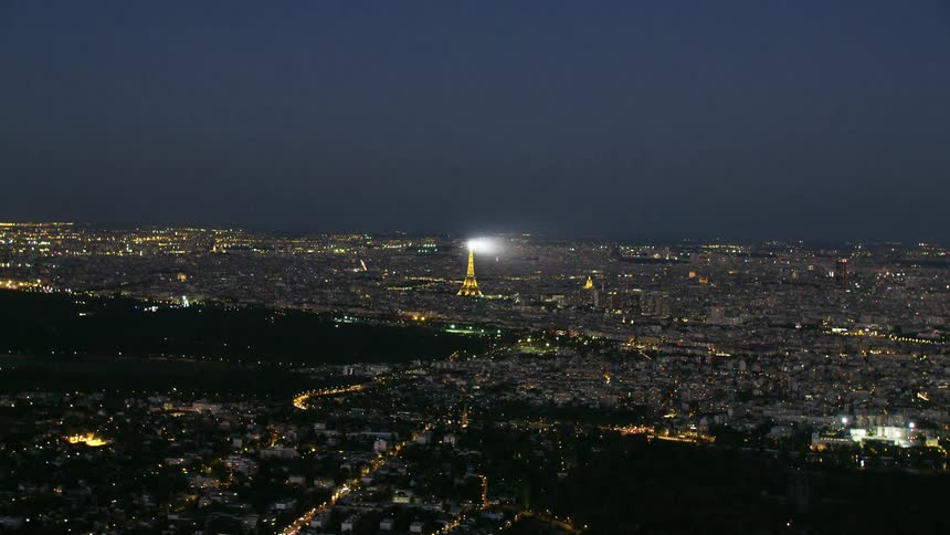A light beam is shining from the eiffel tower at dusk