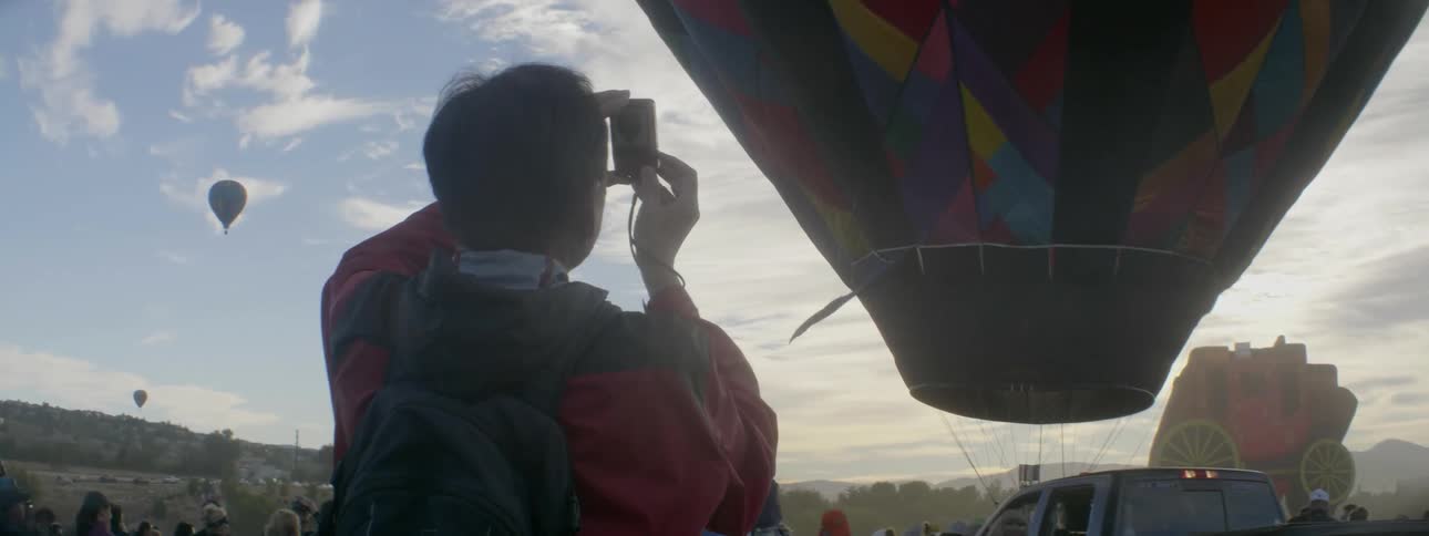 A man takes photos of hot air balloons in the air