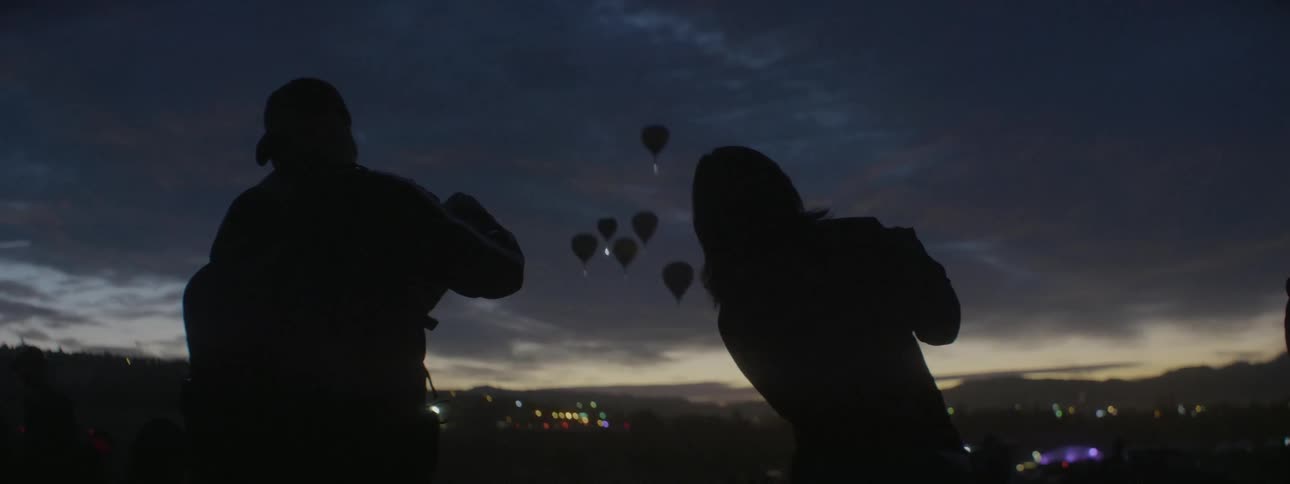 People photograph hot air balloons flying in the sky