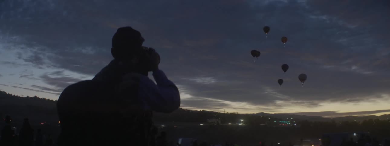 A man takes photos of hot air balloons in the air
