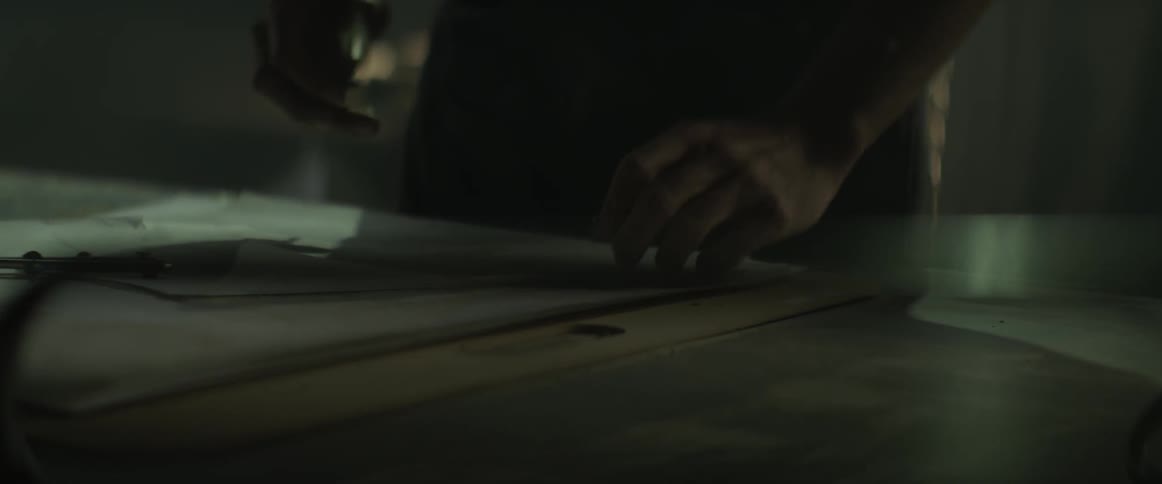 A man picks up a pencil and writes on paper