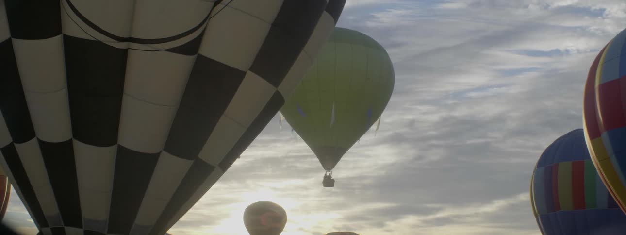 A hot air balloon is rising into a cloudy sky
