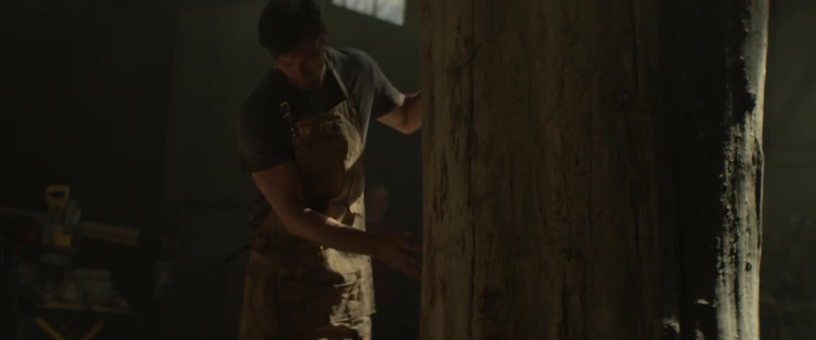 A man rubs a large tree trunk in a workshop
