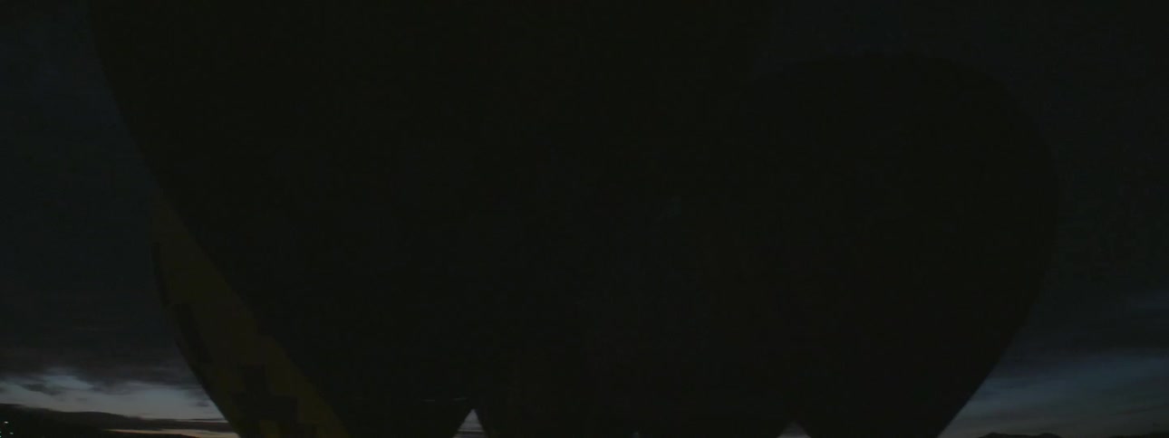 The burners on a hot air balloon flare up and light up the surrounding area at night