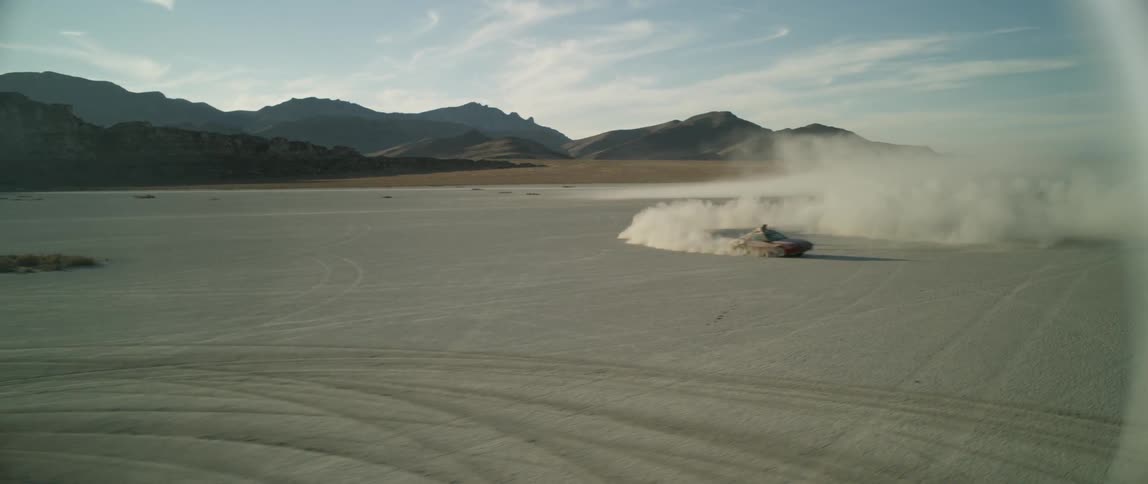 A person does donuts on a dusty plain