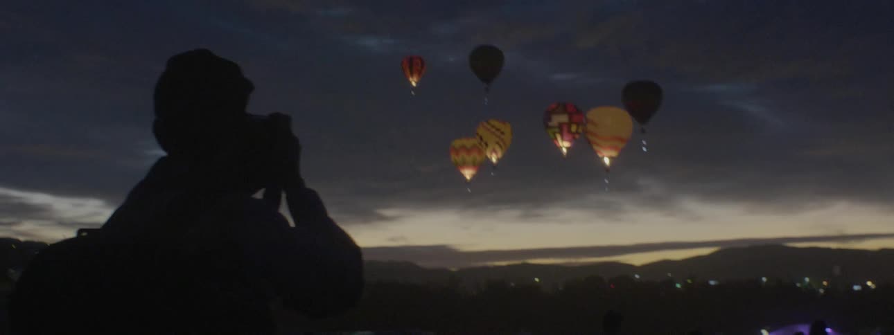 A man takes photographs of flying hot air balloons
