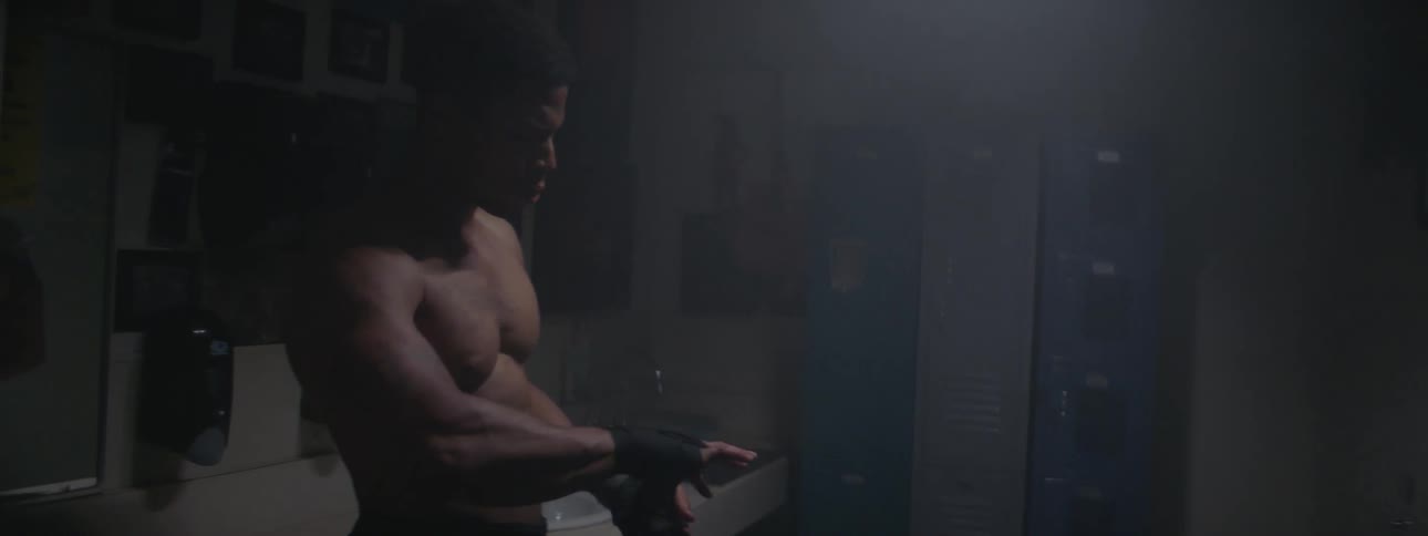 A shirtless man wraps his hand with athletic tape