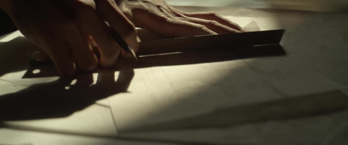 A man uses a ruler to mark blueprints