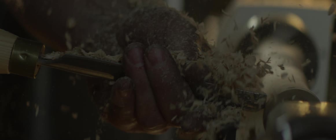 A man shapes a piece of wood on a lathe