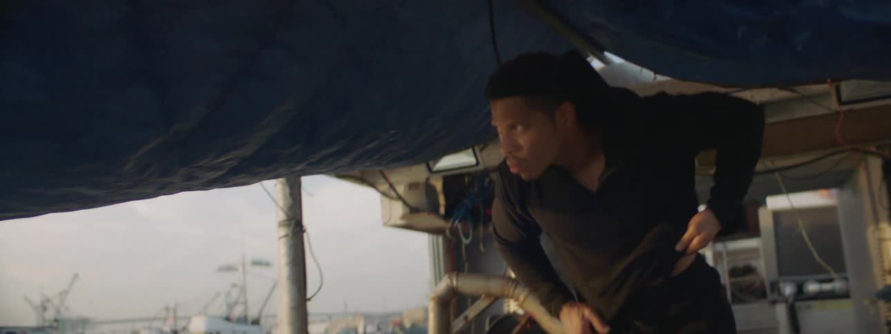 A man puts on a jacket while walking on a fishing boat