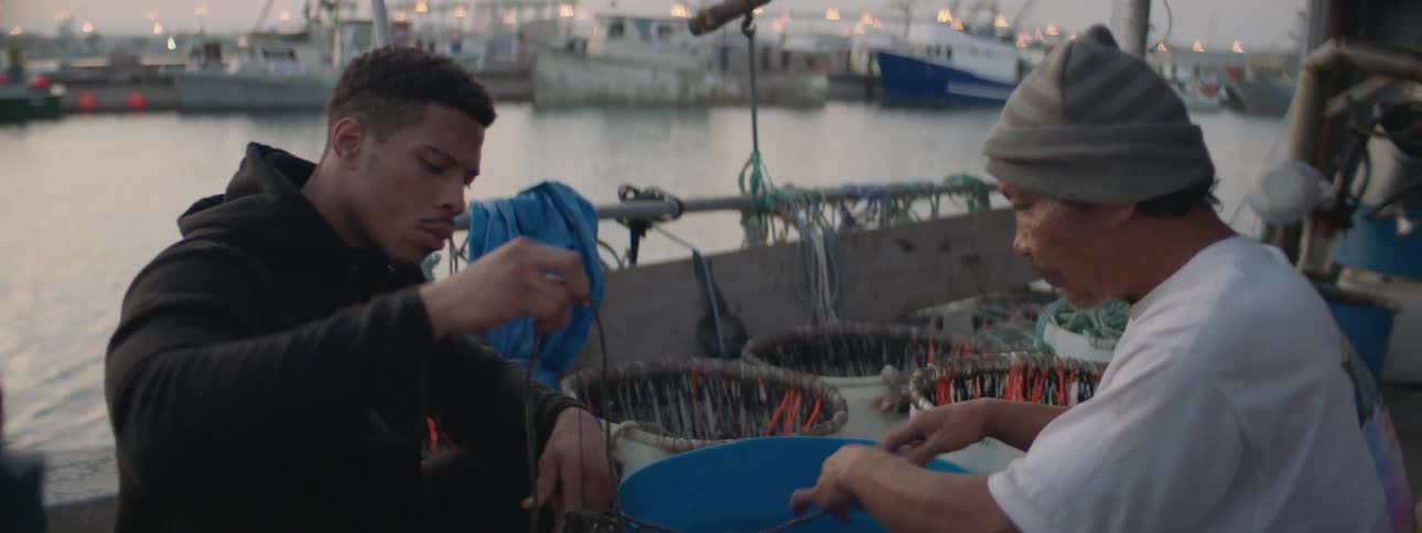 Two men tie ropes on a boat