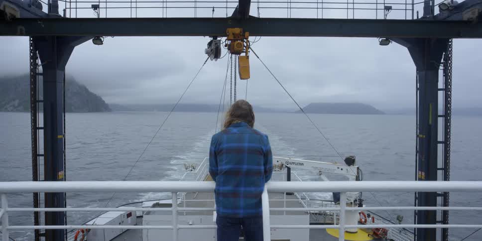 A man looks out at the water on a moving boat