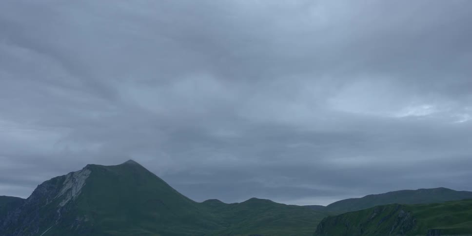 Clouds roll past a mountain range