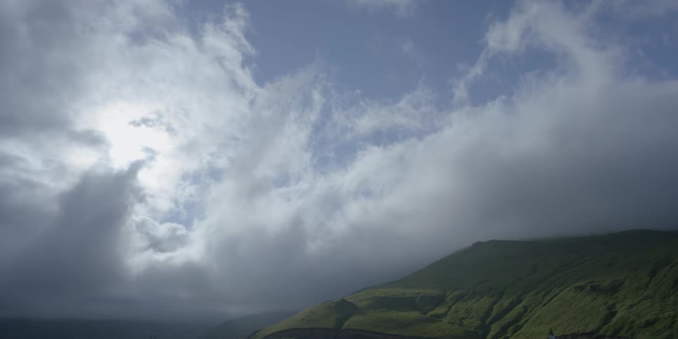 Clouds over a green mountain