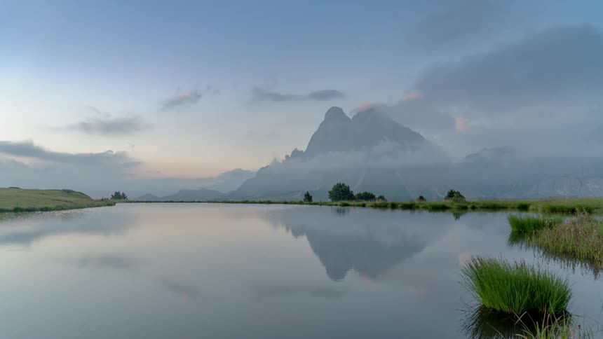 Clouds pass above a lake and a mountain