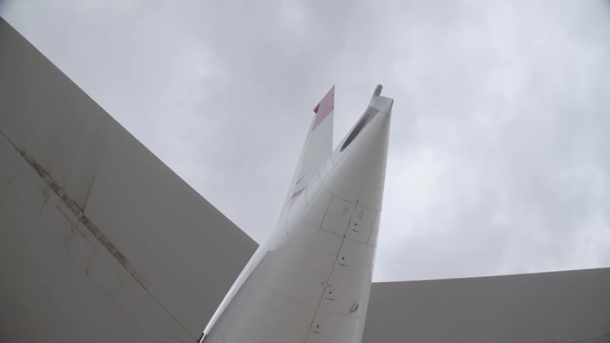 Clouds hover over an airplane sitting on the ground during the day