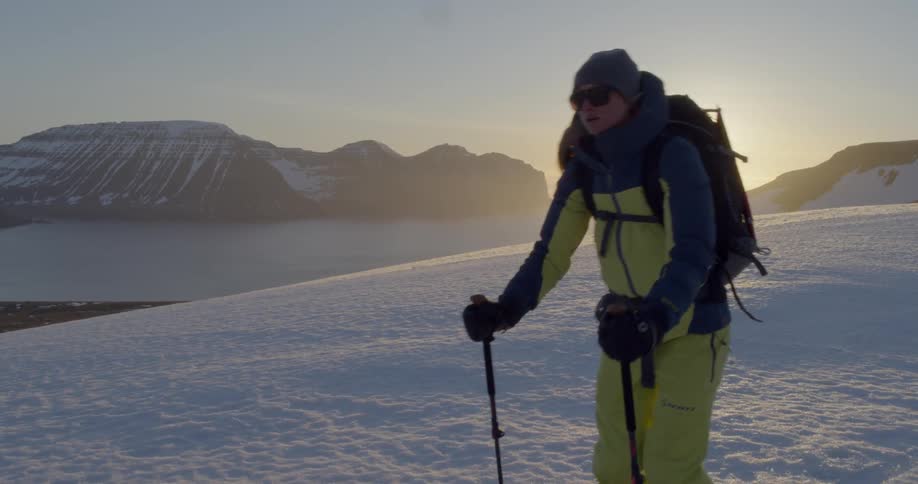 A person is skiing along a mountain ridge at sunrise