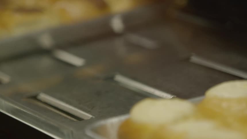 A pan full of pastries is lifted out of place and then put back