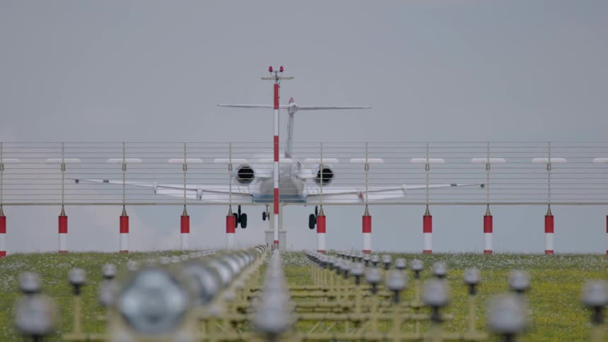 A plane is landing on a runway on an overcast day