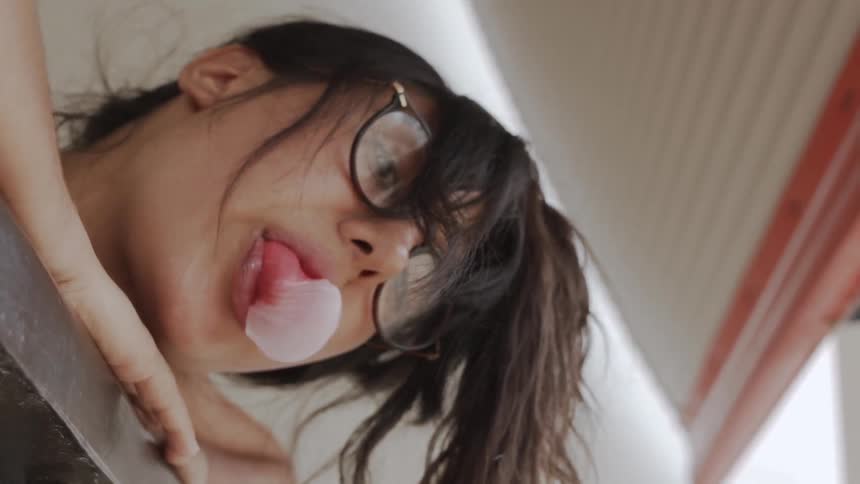 A woman blows a bubble with bubblegum