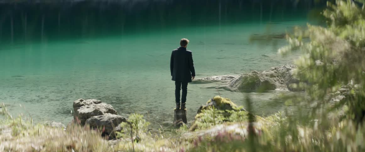 A man is standing in the shallow water shore