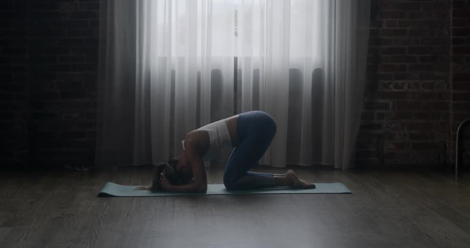 A woman is doing yoga by the window