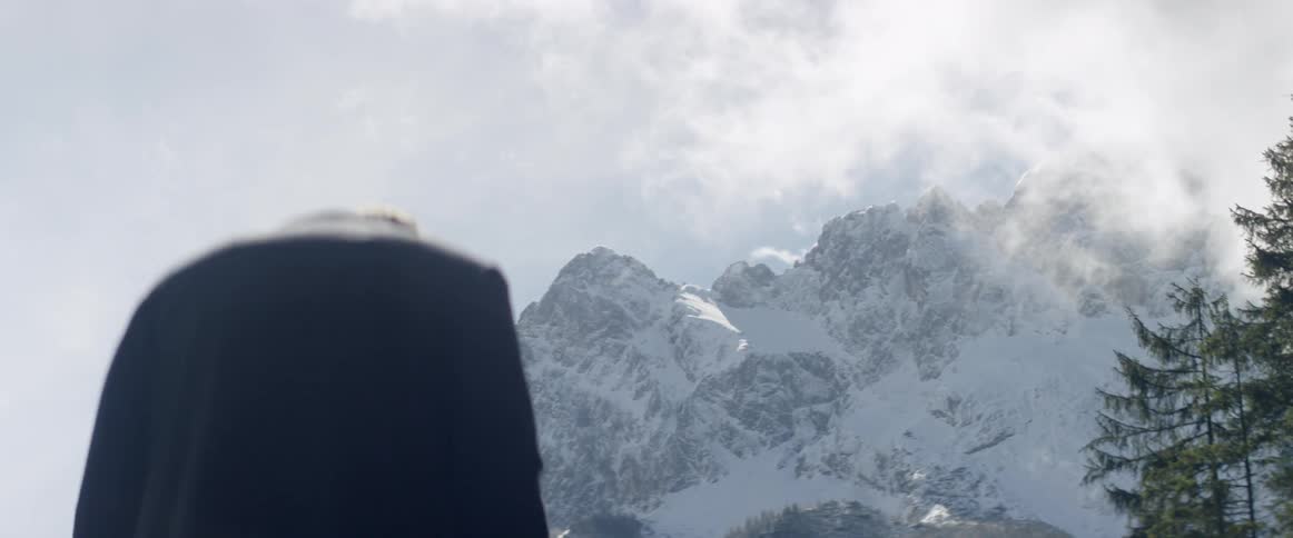A man stands in front of a snowy mountain