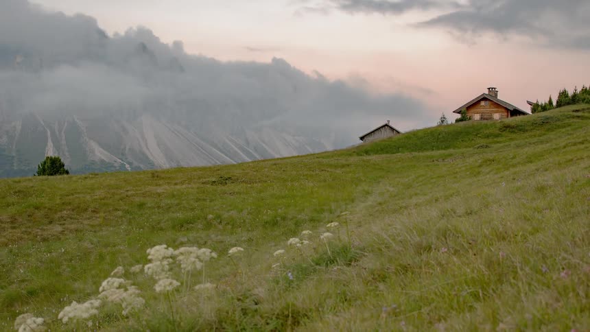 Clouds pass over two buildings in the hills