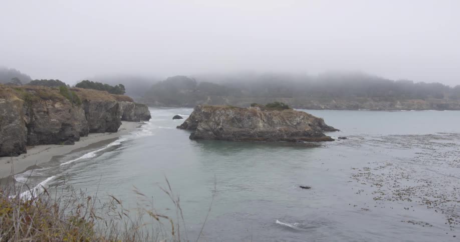 Calm sea crashing on beach next to a cliff