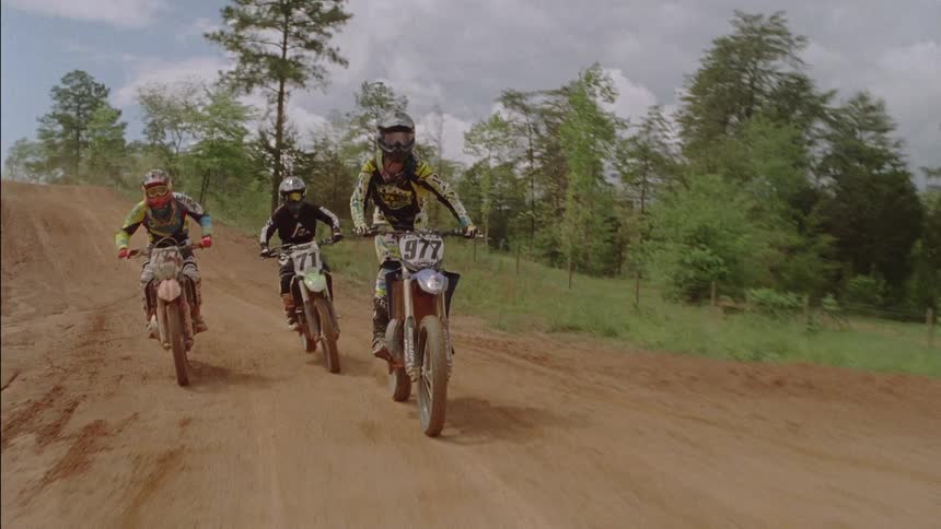 Three people are riding dirt bikes