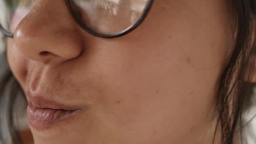 A woman is putting bubble gum in her mouth and chewing it