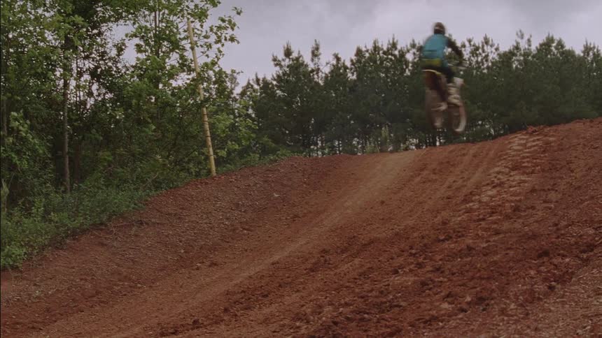 People on dirt bikes make a jump over a hill